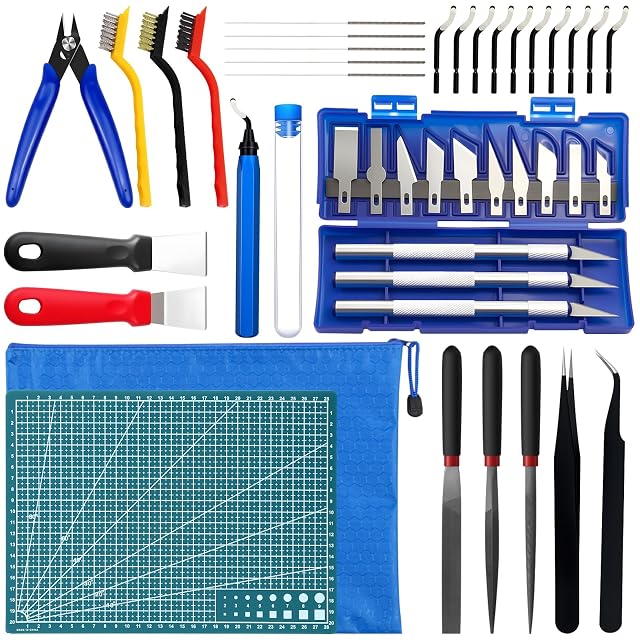 Kit laid out: flush cutter, three brushes, needles, deburrer and ten blades, two scrapers, a knife set in a blue case, a cutting mat, a zip pouch, three files and tweezers