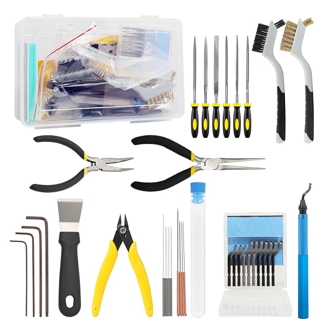 Kit laid out: clear box, six files, two brushes, two long-nose pliers, flush cutter, scraper, four hex keys, needles in a tube, ten blades and a blue deburrer