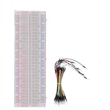 Long white solderless breadboard with red and blue rail lines along both edges, beside a bundle of flexible jumper wires