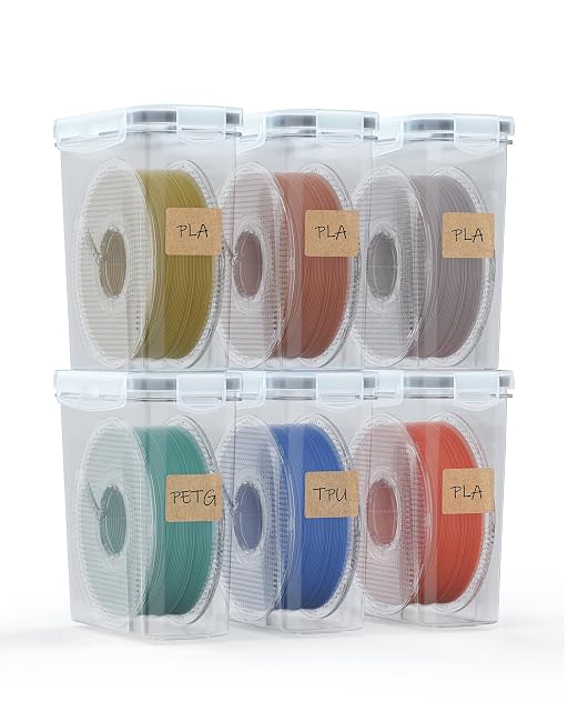 Six transparent boxes stacked in two rows, each holding a spool with a kraft label reading PLA, PETG or TPU